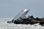 An investigator looks at a boat overturned on a jetty, Sunday, Sept. 25, 2016, off Miami Beach, Fla. Authorities said that Miami Marlins starting pitcher Jose Fernandez was one of three people killed in the boat crash early Sunday morning. Fernandez was 24. (AP Photo/Gaston De Cardenas)