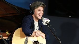 Niall Horan holds an acoustic guitar at the mic in the SiriusXM studios.