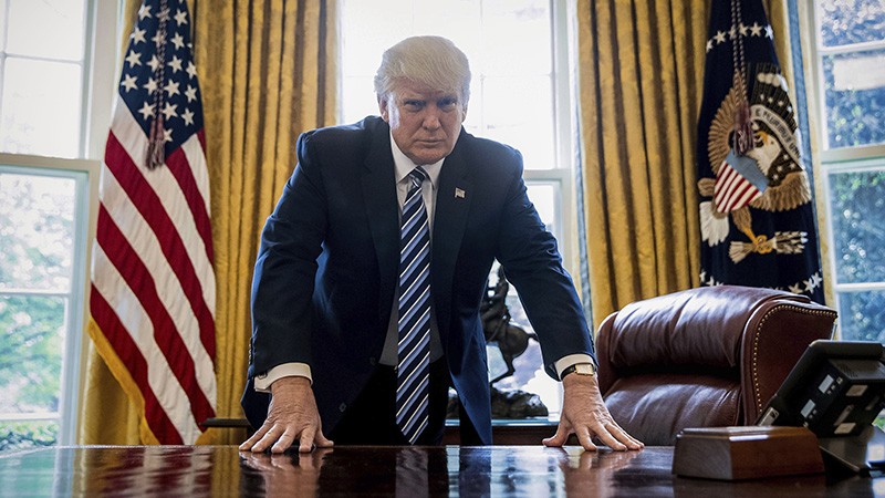 President Donald Trump poses for a portrait in the Oval Office in Washington.