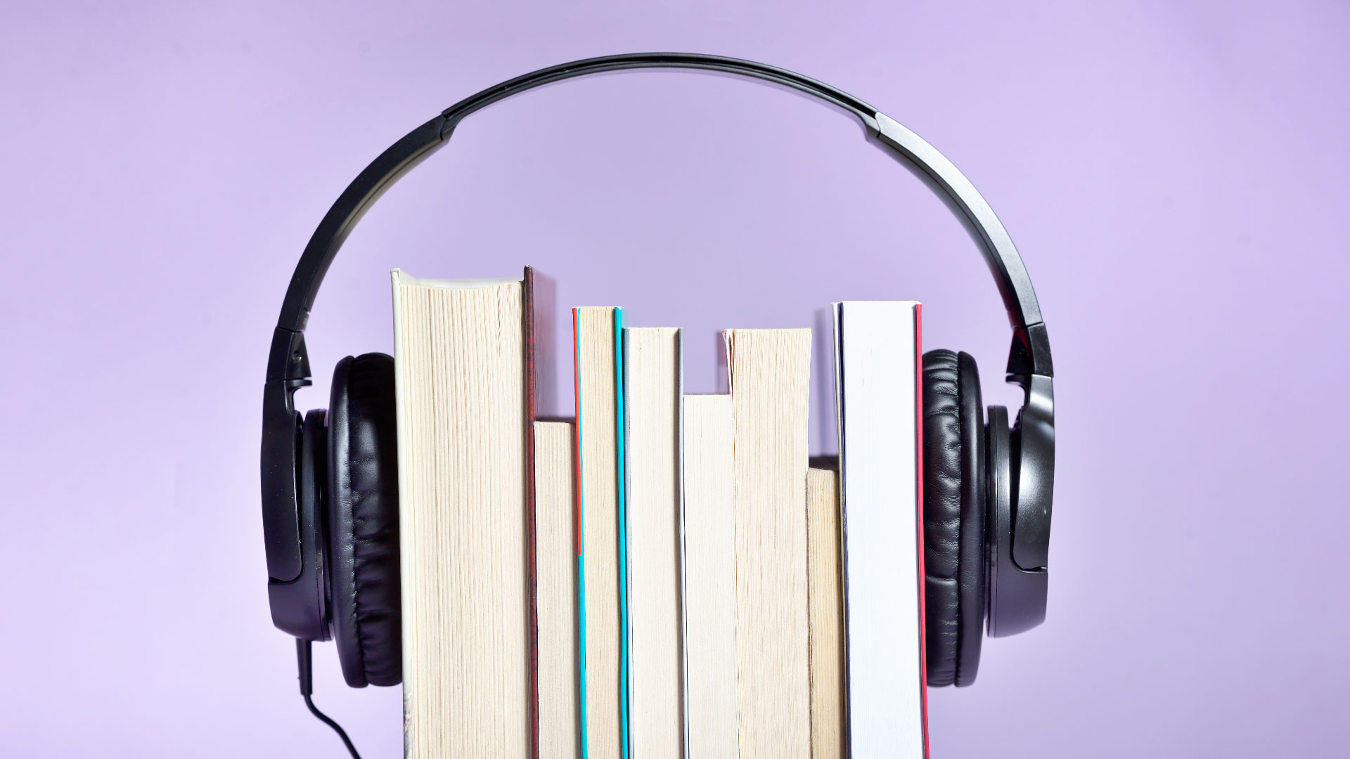 Close-Up Of Books With Headphones Against Purple Background
